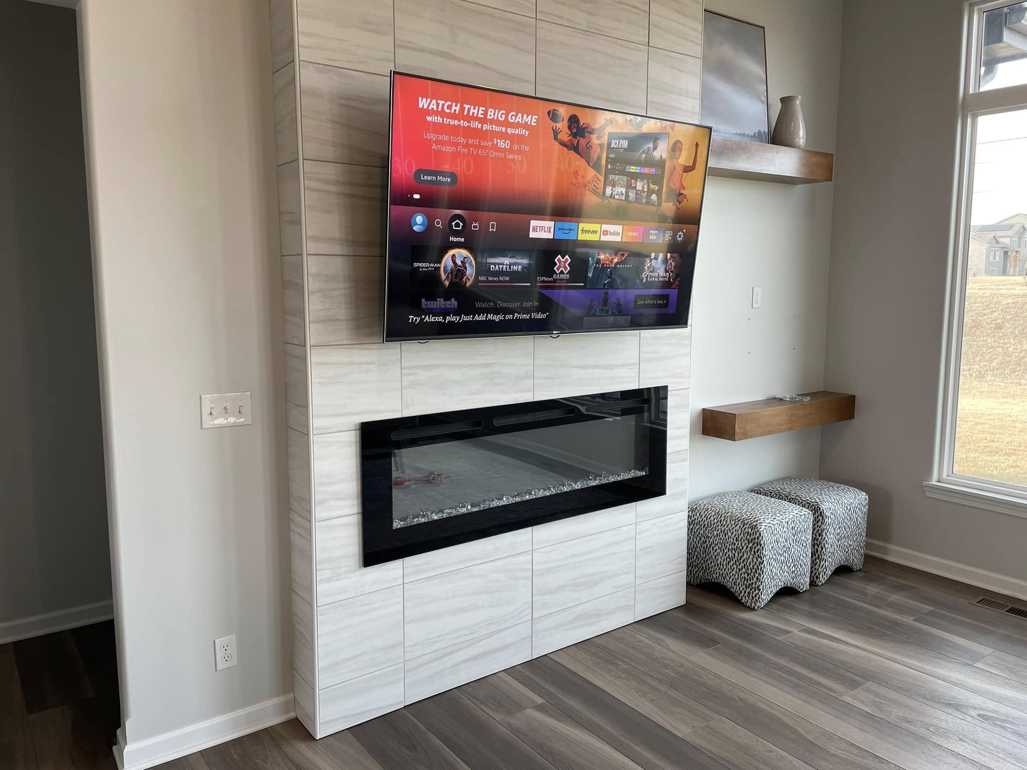 After: completed tile fireplace wall with mounted TV and floating shelves