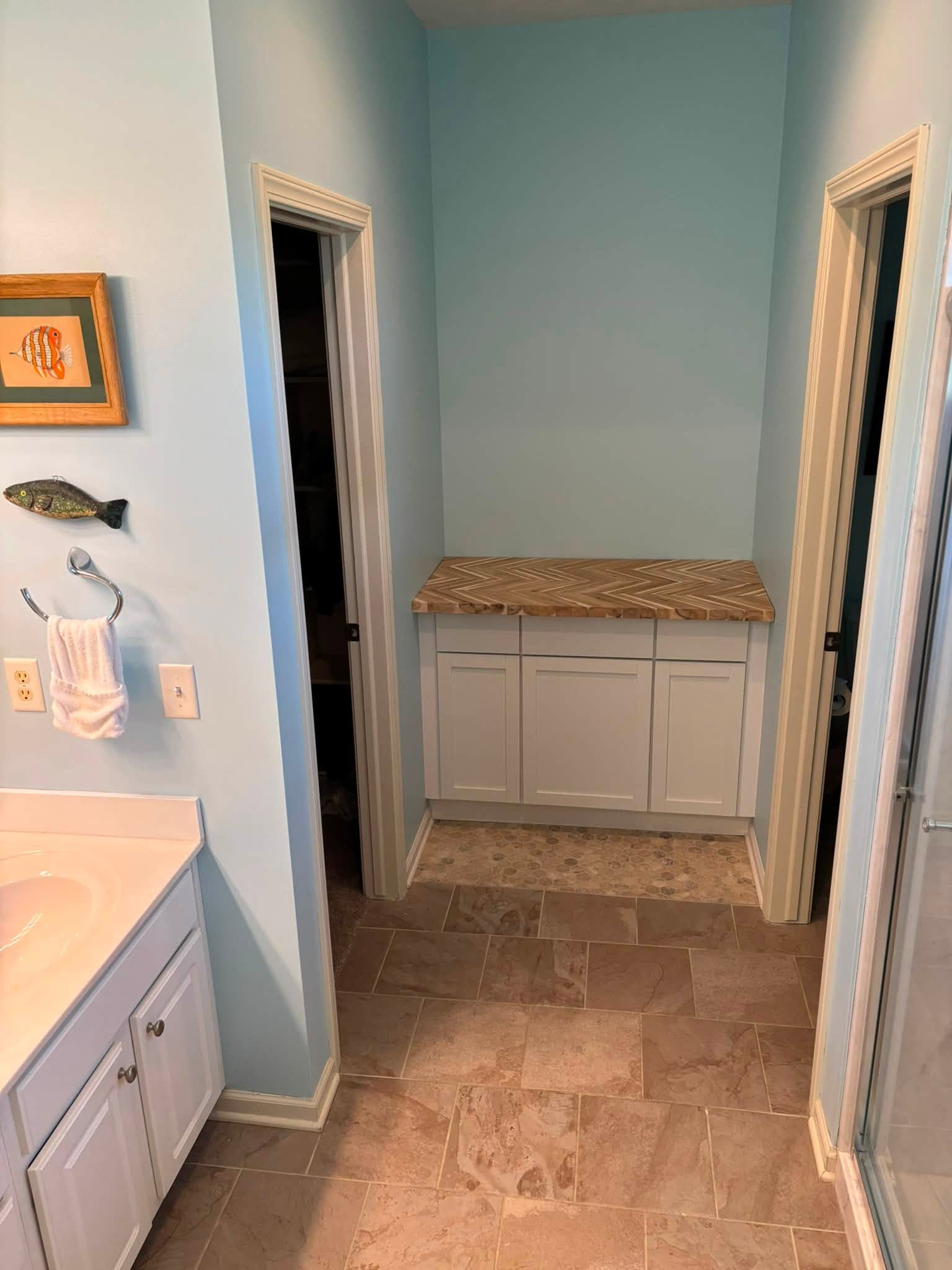 After: finished bathroom with stone tile floor and a white cabinet topped with herringbone butcher block