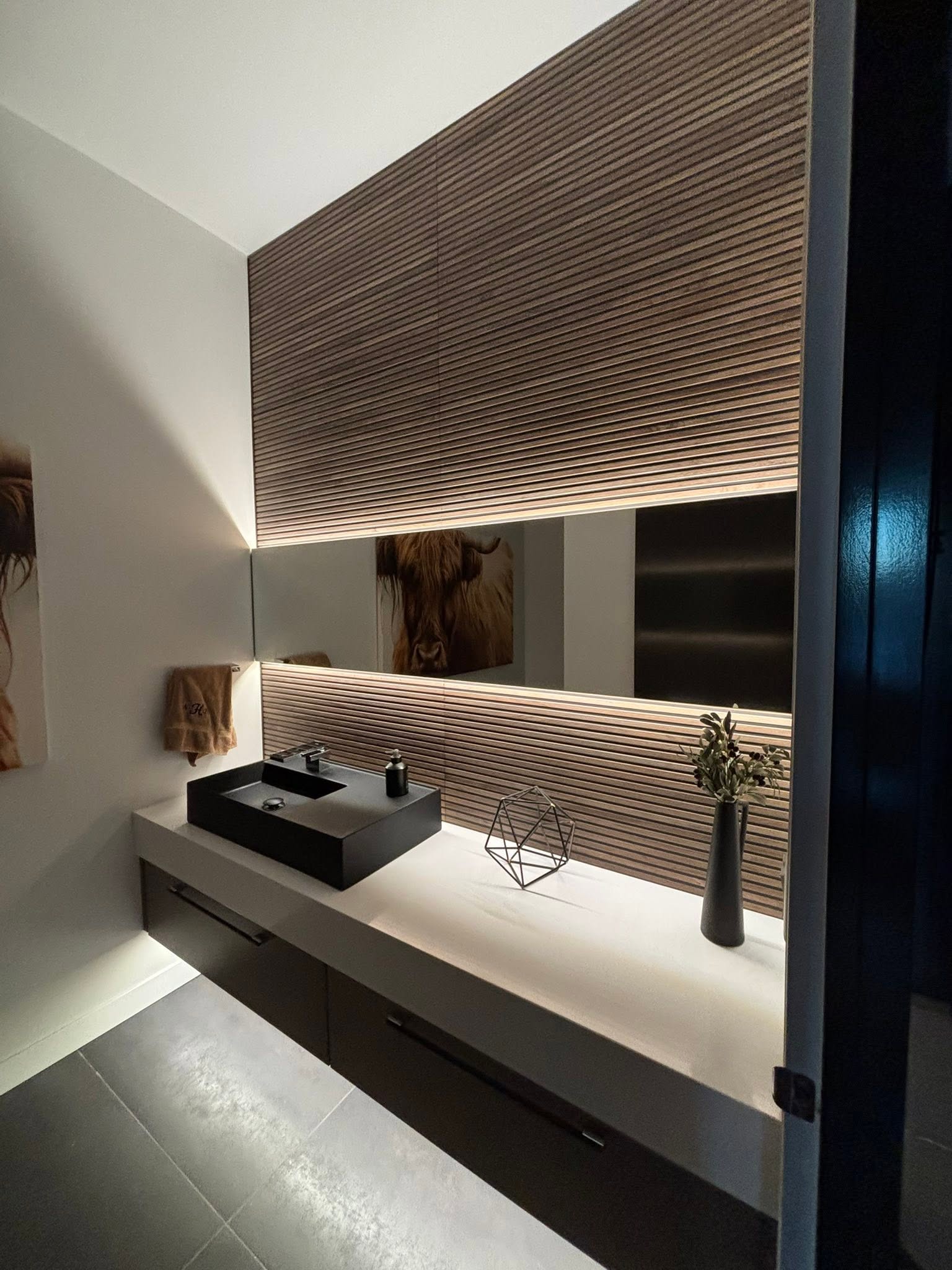 Luxury bathroom with floating vanity, wood slat wall, and backlit mirror