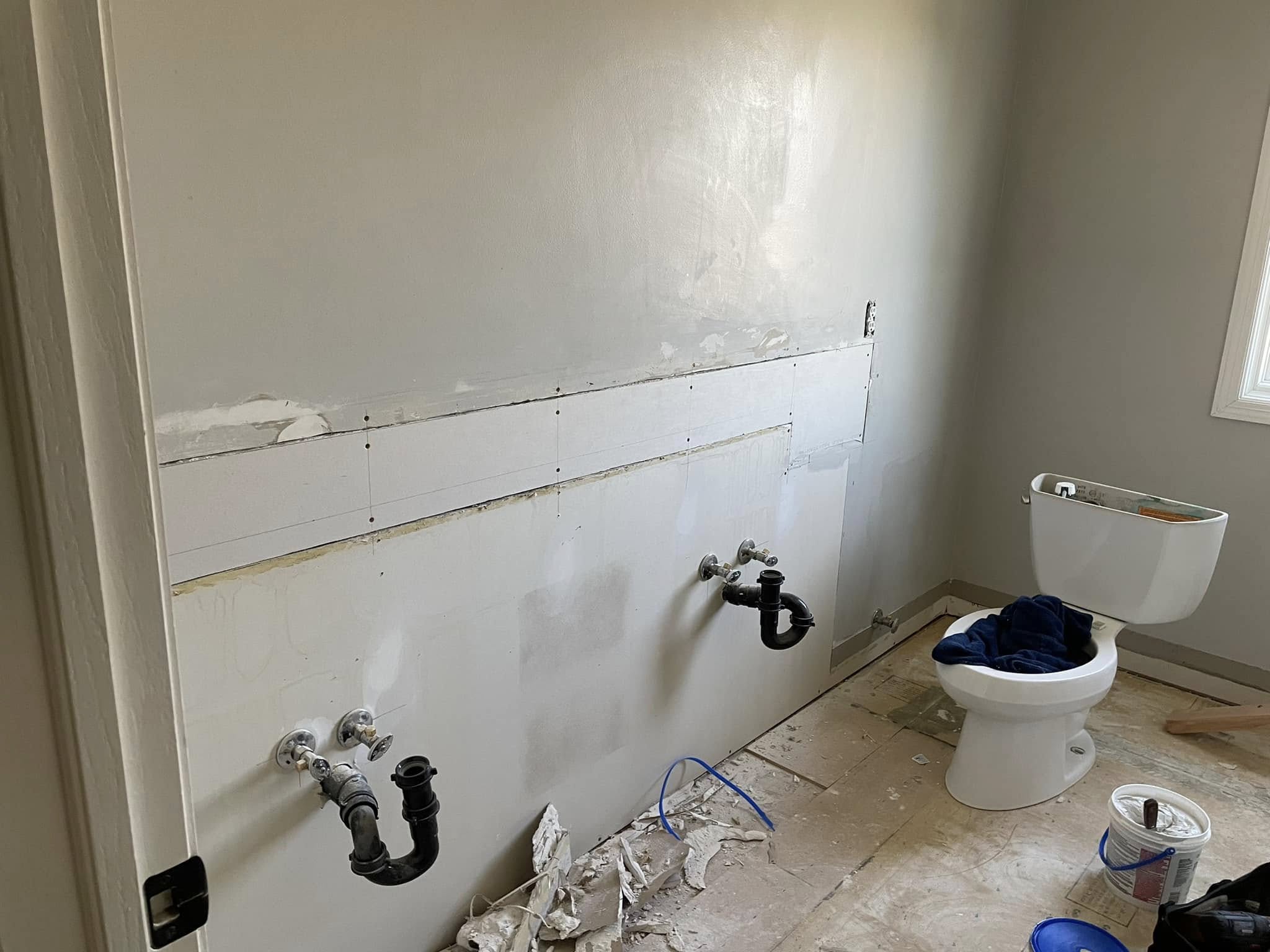 Before: gutted bathroom with exposed plumbing