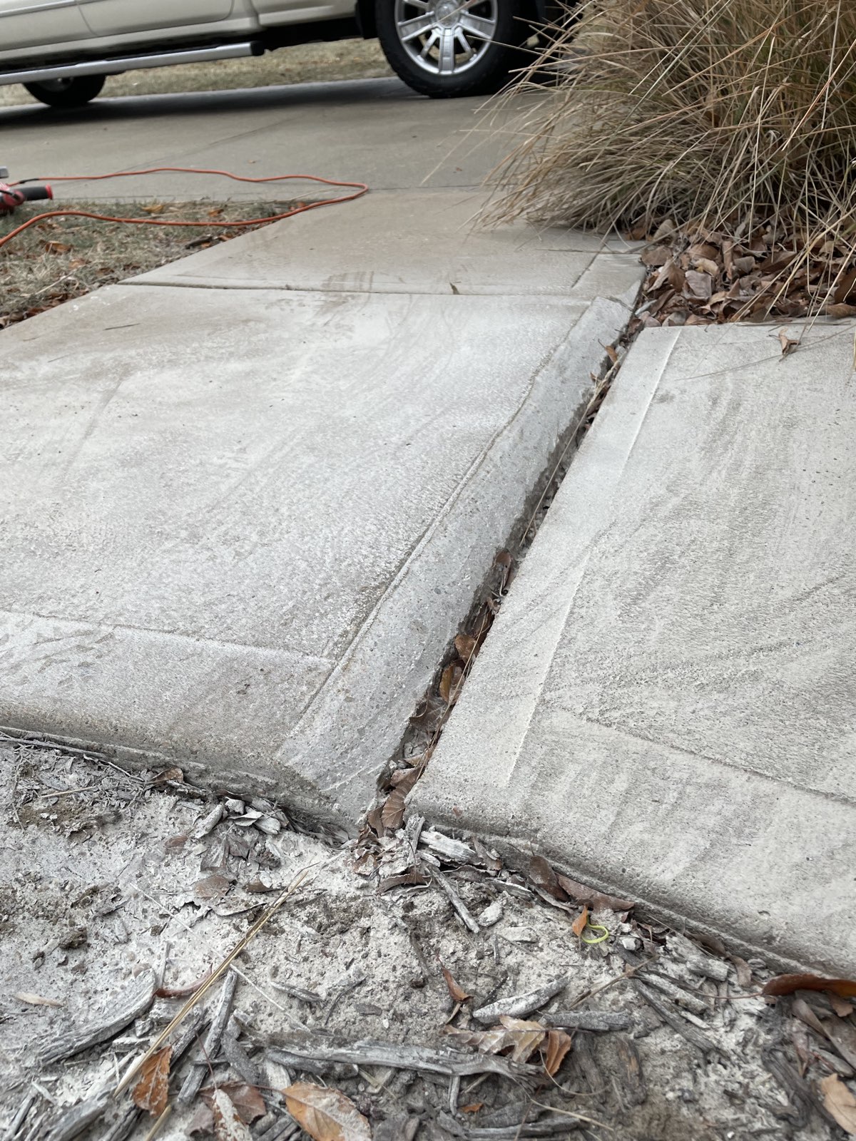 Before: uneven sidewalk slabs with a raised edge and trip hazard