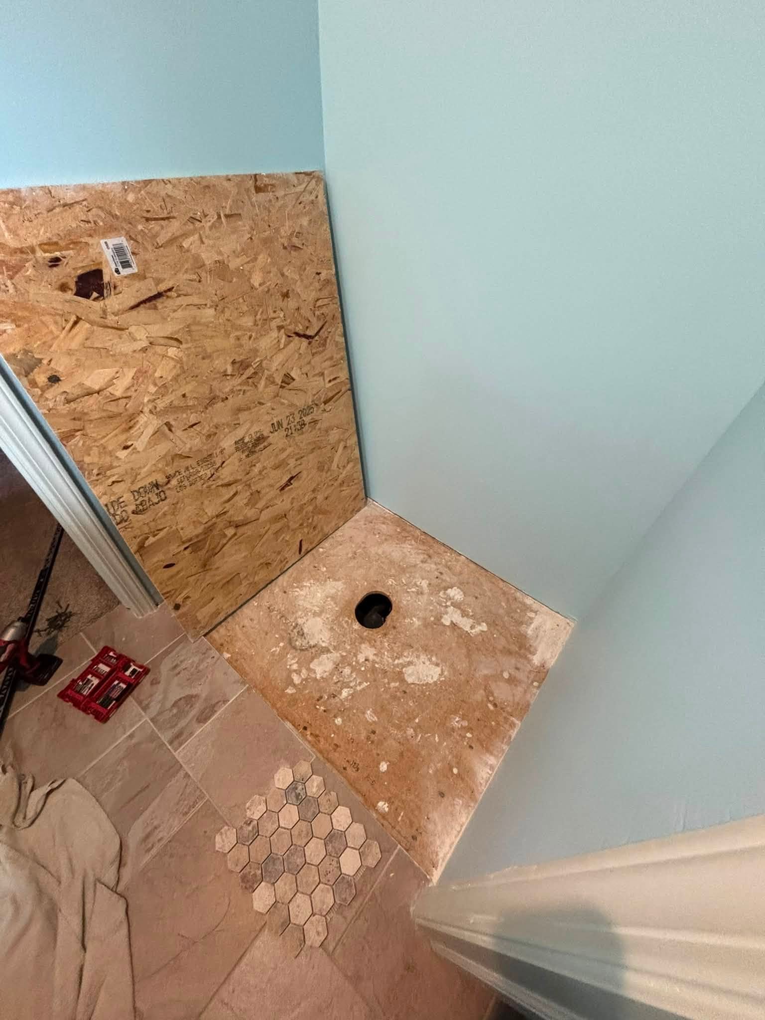 Before: bathroom stripped to bare subfloor with the toilet flange exposed