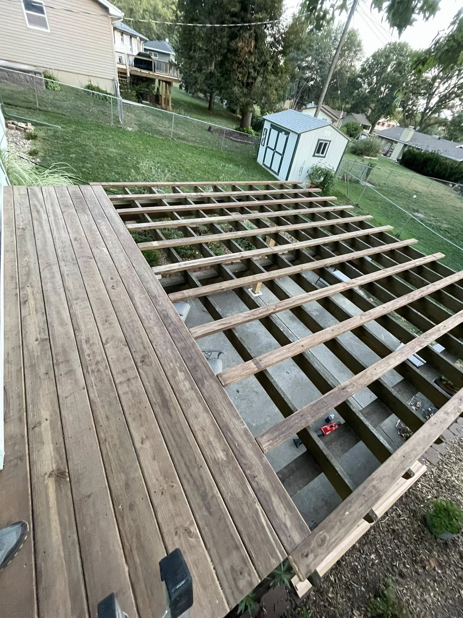 Deck under construction with joist framing exposed and decking boards partially laid
