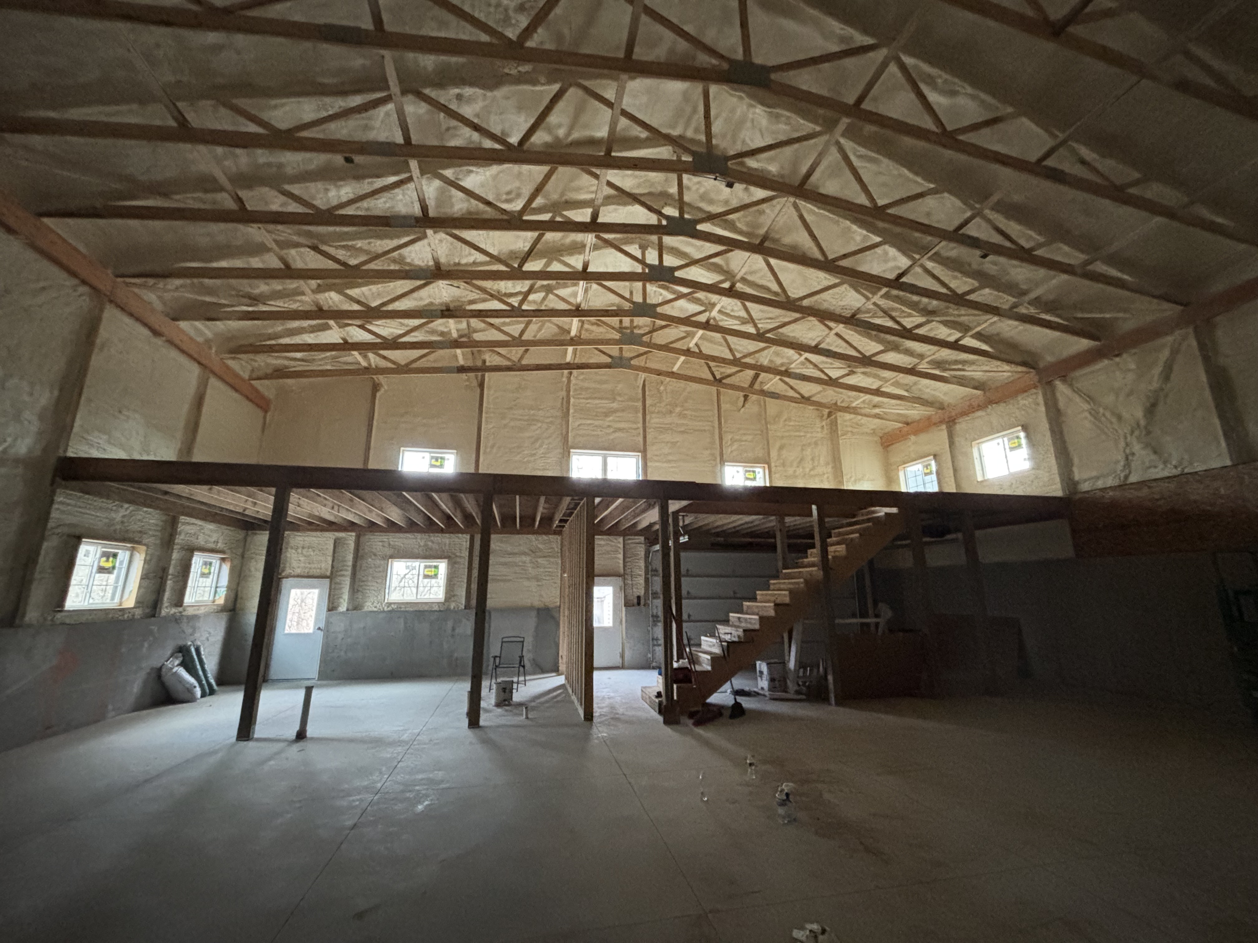 Large open space with spray foam insulation, framing, and loft structure
